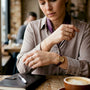 Close-up of hands fastening gold bracelet in office