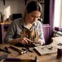Female artisan filing silver ring on workbench