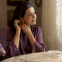 Woman placing timeless diamond earrings by vanity