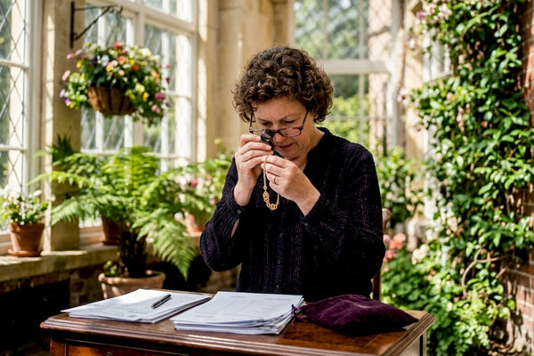 Woman appraising gold necklace at desk