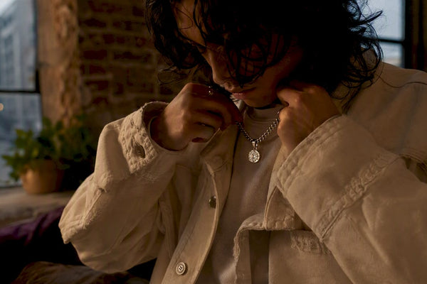 Hands layering ethical gemstone pendant with streetwear