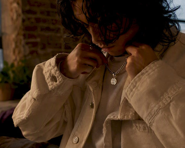 Hands layering ethical gemstone pendant with streetwear