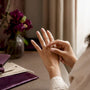 Hand placing moissanite ring on finger near vanity