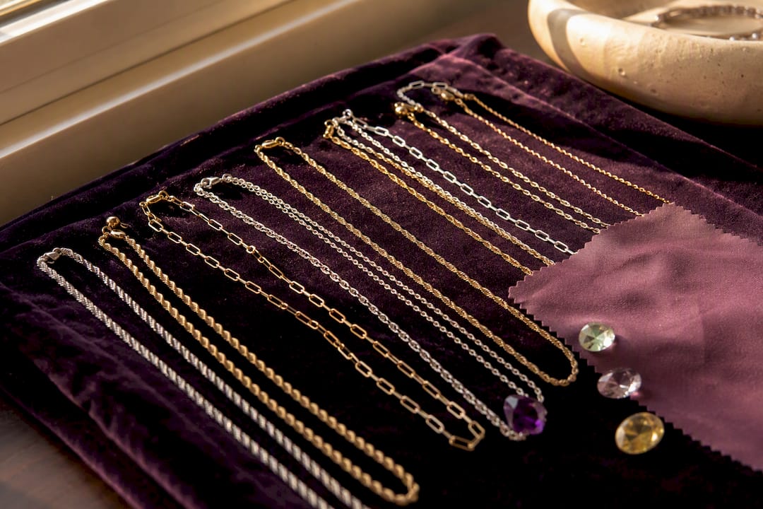 Layered necklaces on warm cream fabric