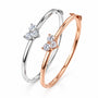 Two diamond-studded bangles, one silver and one rose gold, on a light background.